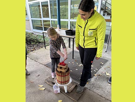 Der-Saft-fließt-schülerin-bedient-Apfelpresse